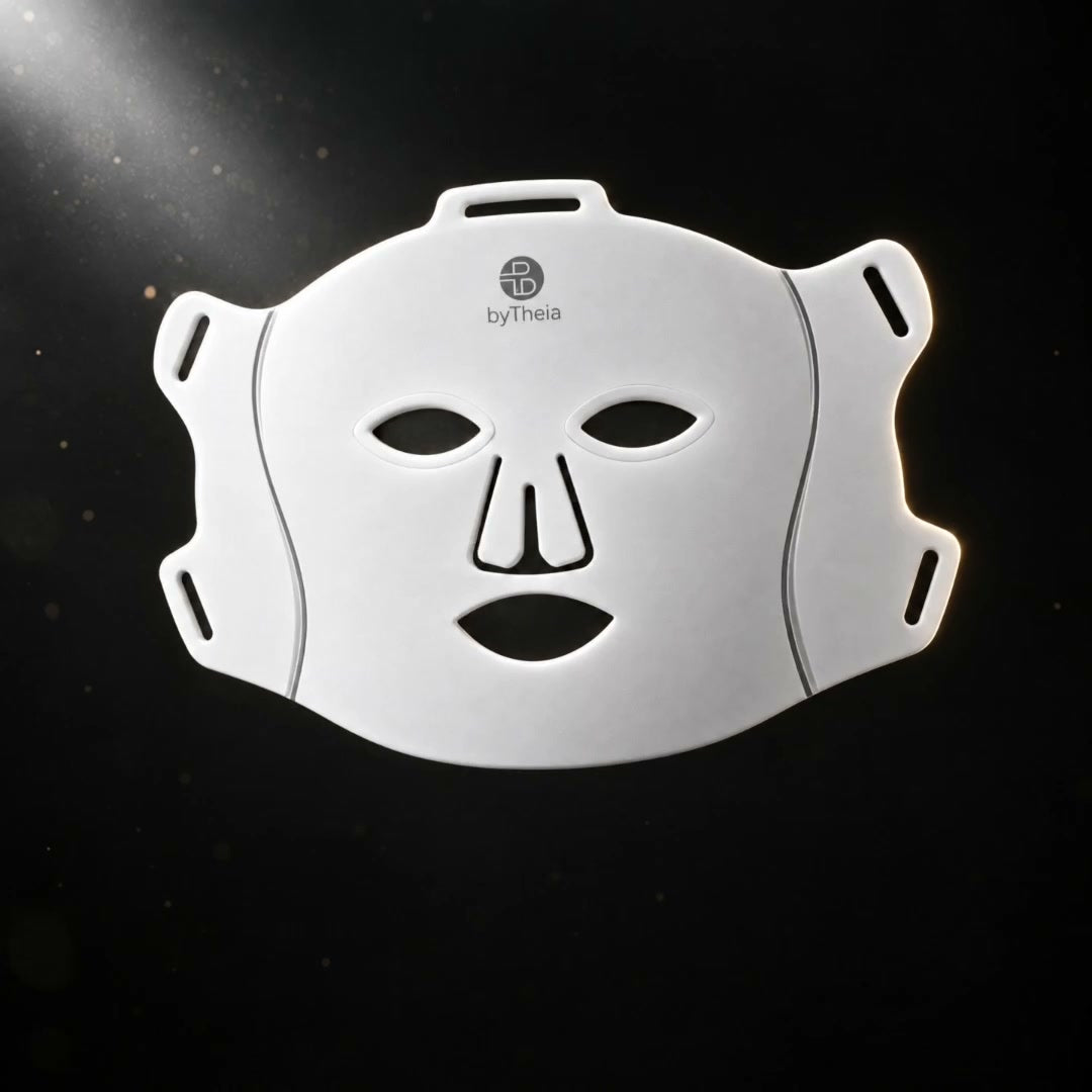 The white byTheia LED face mask on a dark background, lit from the upper left.