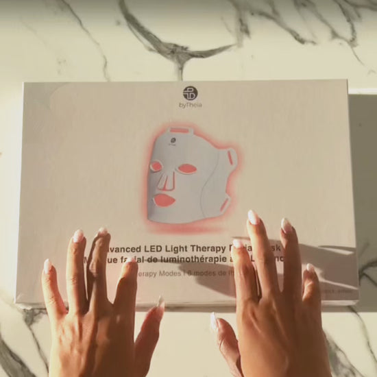 Unboxing video: hands opening the byTheia LED face mask box on a marble counter.